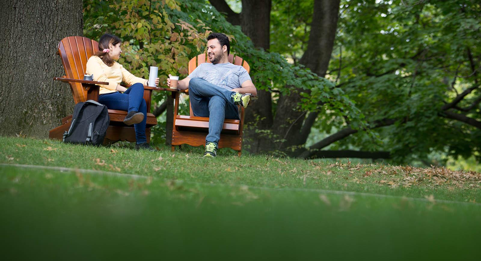 Photo of two students seated on Adirondack chairs outside on 足球波胆平台