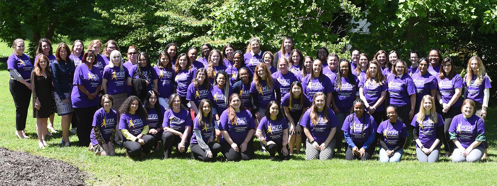 Photo of a large group of Chatham University students wearing purple New 领导 Program T-shirts, 一起在外面的草地上摆姿势. 